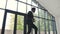 Happy young businessman dressed in suit is dancing in lobby of office with documents paper in hands, and celebrating