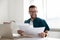 Happy young businessman in glasses looking through paper documents.