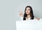 Happy young businesswoman pointing up and showing signboard