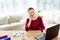 Happy young businesswoman sitting at wood desk, working on laptop and talking on mobile phone with client at home office, copy