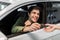 Happy young Caucasian man taking car key from auto dealer, purchasing new vehicle at showroom store