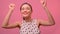 Happy young Caucasian woman dancing in a good mood on a pink background.