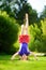 Happy young child playing head over heels on green grass in spring park