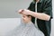 Happy young client sits in chair at men`s hairdresser and cuts hair in barber. Professional male hairdresser cuts a positive youn