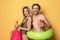 Happy young couple in beachwear with inflatable rings