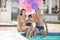 Happy young couple and daughter sitting on the edge of a swimming pool