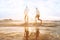 Happy young couple having fun on the beach at sunset, water splash