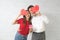 Happy young couple is holding red paper hearts and smiling on blick wall background
