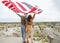 Happy young couple holding a waving American flag in nature. Independence Day, lifestyle, travel concept