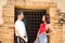 Happy young couple in love, leaning on the brick frame of a door with a grille, smiling. Concept love, passion, desire, lovers,