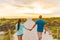 Happy young couple in love walking on romantic evening beach stroll at sunset. Lovers holding hands on summer holidays