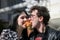 Happy young couple in morning and having breakfast. Cheerful man and woman bite a croissant at the same time