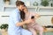 Happy young couple in pajamas watching online content in a smart phone and smiling while cooking in kitchen at home