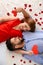 Happy young couple with red hearts lying on bed at home. Celebration of Saint Valentine\'s Day