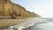 Happy young couple relaxes on sandy beach with high sandstone cliffs. Honeymoon concept