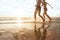 Happy young couple running to the sea on the beach at sunset, silhouettes of man and woman