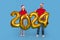 Happy Young Couple In Santa Hats Holding Golden 2024 Balloons In Hands