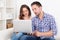 Happy young couple sitting on couch using laptop