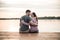 Happy young couple sitting on the dock by the lake, hugging