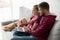 Happy young couple sitting on sofa using laptop computer togethe