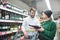 Happy young couple in a supermarket with a bottle of wine in their hands. Choice of wine in supermakret