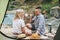 Happy young couple travelers in casual outfits having lunch near tent in mountains. Local tourism, weekend trip