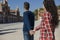 happy young couple walking by the city. Holding hand of girlfriend following him, view from behind. Lifestyle