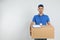 Happy young courier with cardboard box and clipboard on background. Space for text
