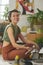 Happy young creative woman in casual attire sitting on the floor of studio