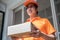 Happy young delivery man in the orange uniform standing with  parcel box to send to customers