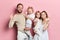 Happy young family with adoravle little daughters posing on pink background