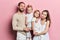 Happy young family with adoravle little daughters posing on pink background