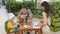 Happy young family with a baby eating on the open air in a cafe. Everyone is sitting on small wooden chairs