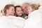 Happy young family cuddling together in bed