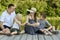 Happy young family, father mother and two little sons are sitting on the river pier