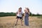 Happy young family. A father, a pregnant mother, and two little sons on their backs. Beveled wheat field on the background. Sunset