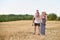 Happy young family. A father, a pregnant mother, and two little sons on their backs. Beveled wheat field on the background. Sunset