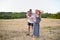 Happy young family. A father, a pregnant mother, and two little sons on their backs. Beveled wheat field on the background. Sunset