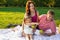 Happy young family having picnic at meadow