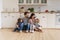 Happy young family with kids relax on warm kitchen floor