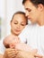 Happy young family of mother, father and newborn baby in their a