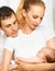 Happy young family of mother, father and newborn baby in their a