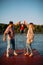 Happy young family raise the baby boy by the hands up on river background. Summer photography for blog about family