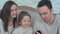 Happy young family sitting on the sofa with father using the phone