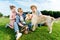 happy young family stroking dog while sitting on green grass