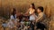 Happy young family of three having picnic in wheat field together.