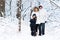 Happy young family of three walking in snowy forest