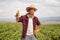 Happy young farmer with gloves showing thumbs up on a grapevine field