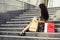 Happy young fashion woman with shopping bags sitting on steps