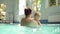 Happy young father with beard is hanging out with his little son in the closed swimming pool. Whirling him around above